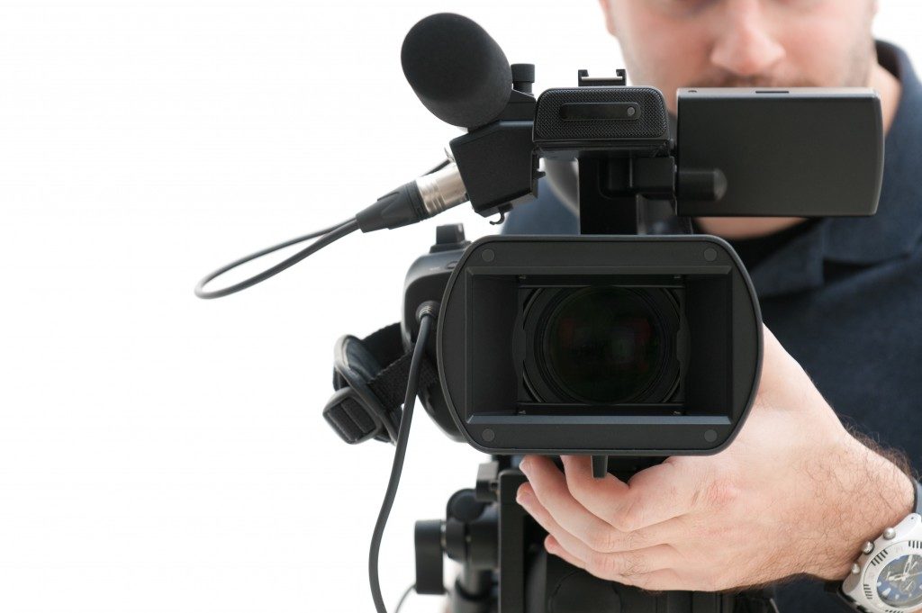 Video camera operator working with his professional equipment isolated on white background