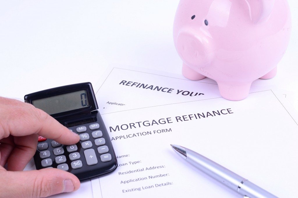small calculator and piigy bank ont top of a mortgage refinance application form