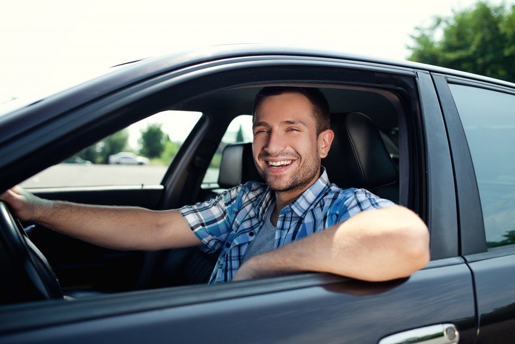 man smiling, driving his car
