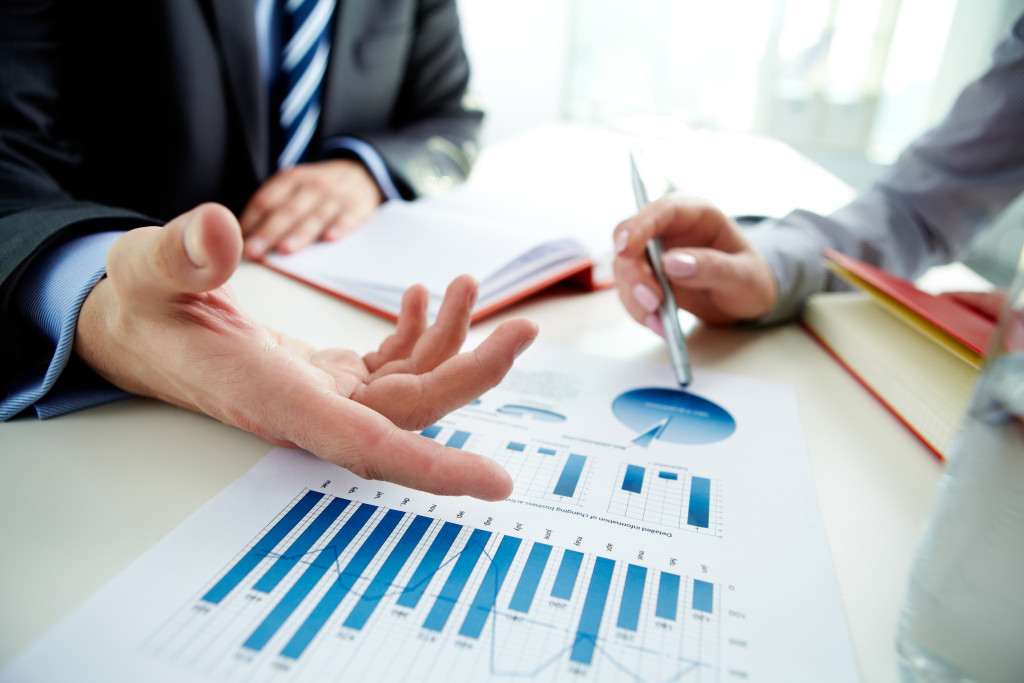 a businessman talking to a woman having a discussion about graphs